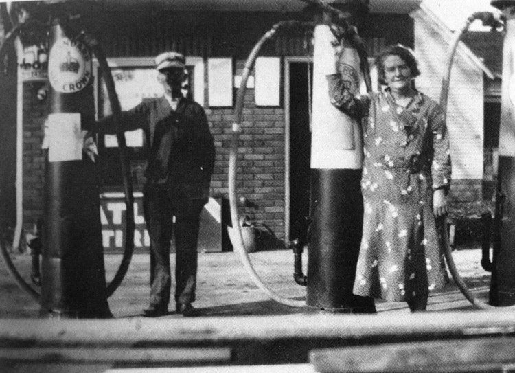 A man and a woman standing at the gas pumps
